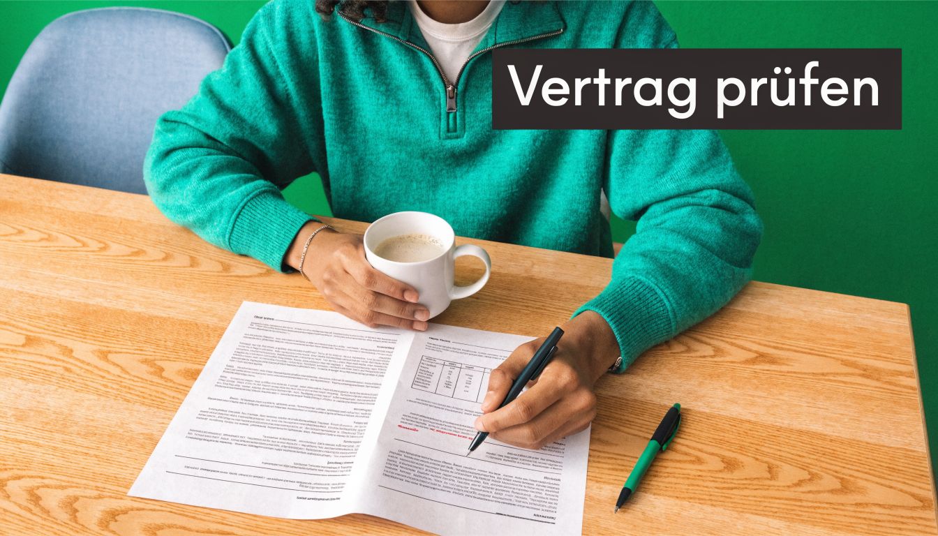 Eine Person mit grünem Pullover sitzt an einem Holztisch, trinkt Kaffee und prüft konzentriert wichtige Vertragsunterlagen.